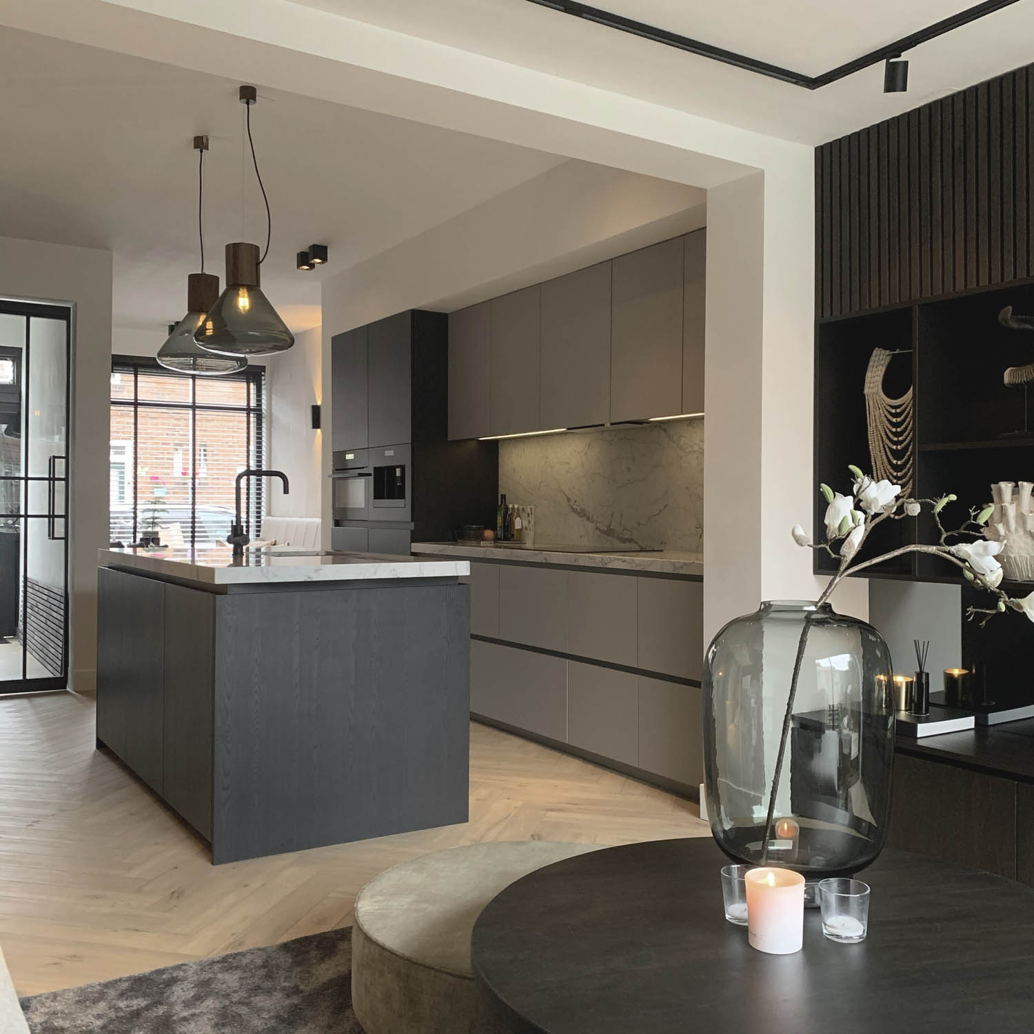 Sophisticated open-plan kitchen with sleek grey cabinetry, marble island, Brokis Muffins Wood 03B pendants, luxe décor.
