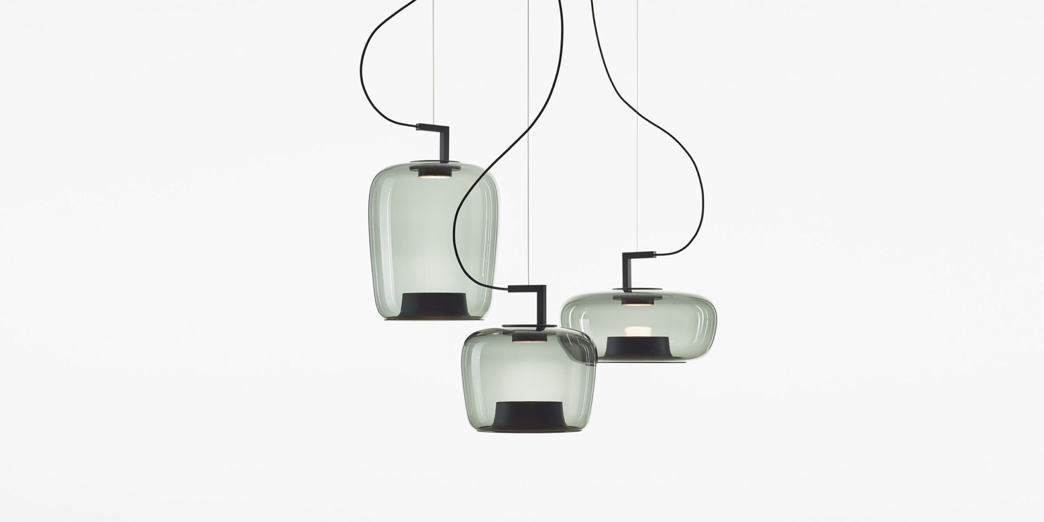 Three Brokis Dome pendant lights with handblown crystal glass shades and black metal fittings against a white backdrop.