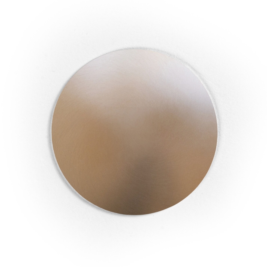 A round, flat metal disc with brushed rose gold finish.