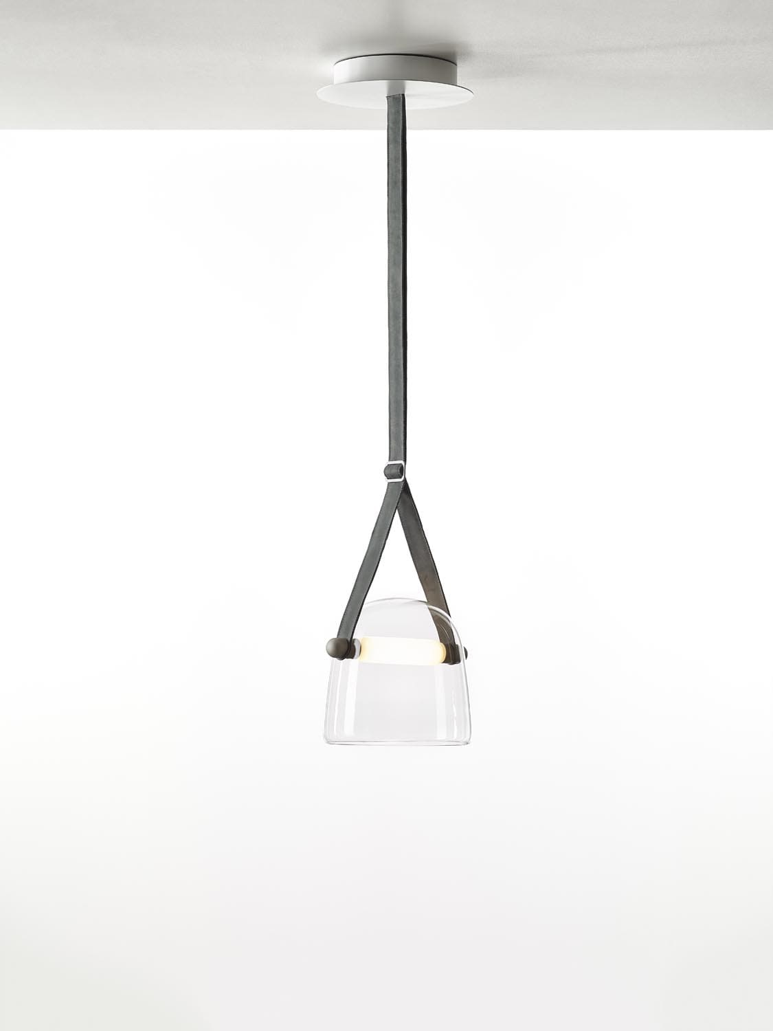 Brokis Mona Medium Pendant, with handblown transparent glass, glows elegantly from a grey leather strap.