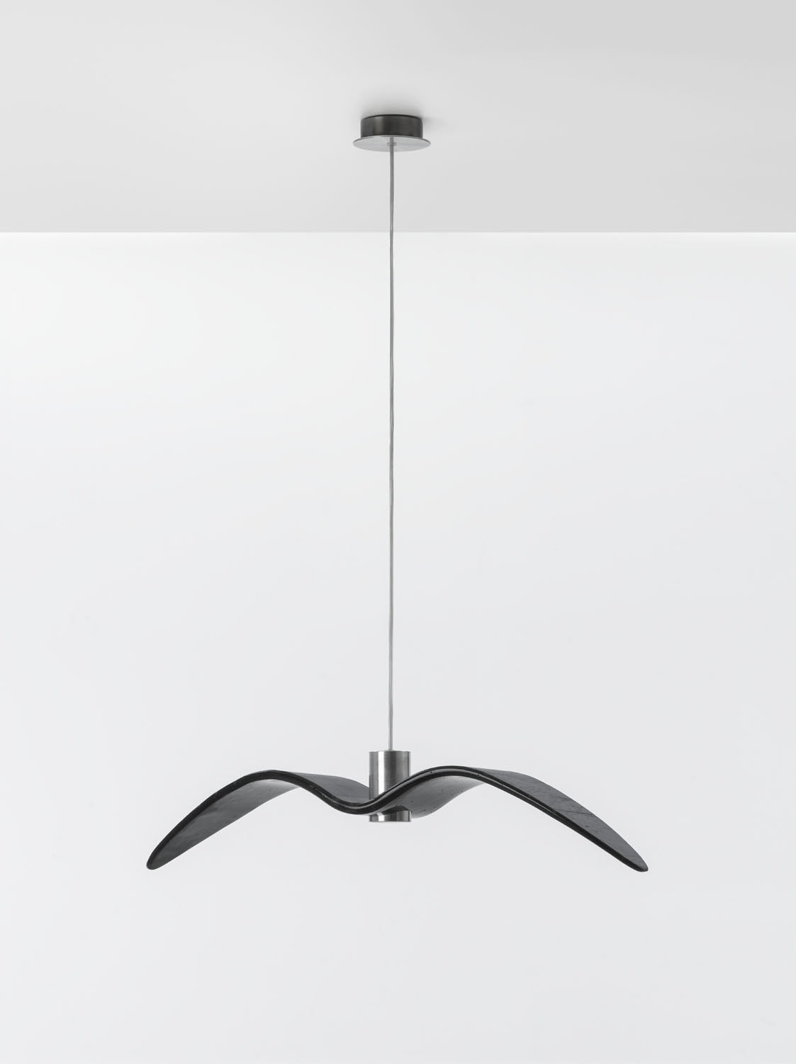 Brokis Night Birds Level Pendant floats from a white ceiling, its sculptural black shade evoking sleek, minimalist luxury.