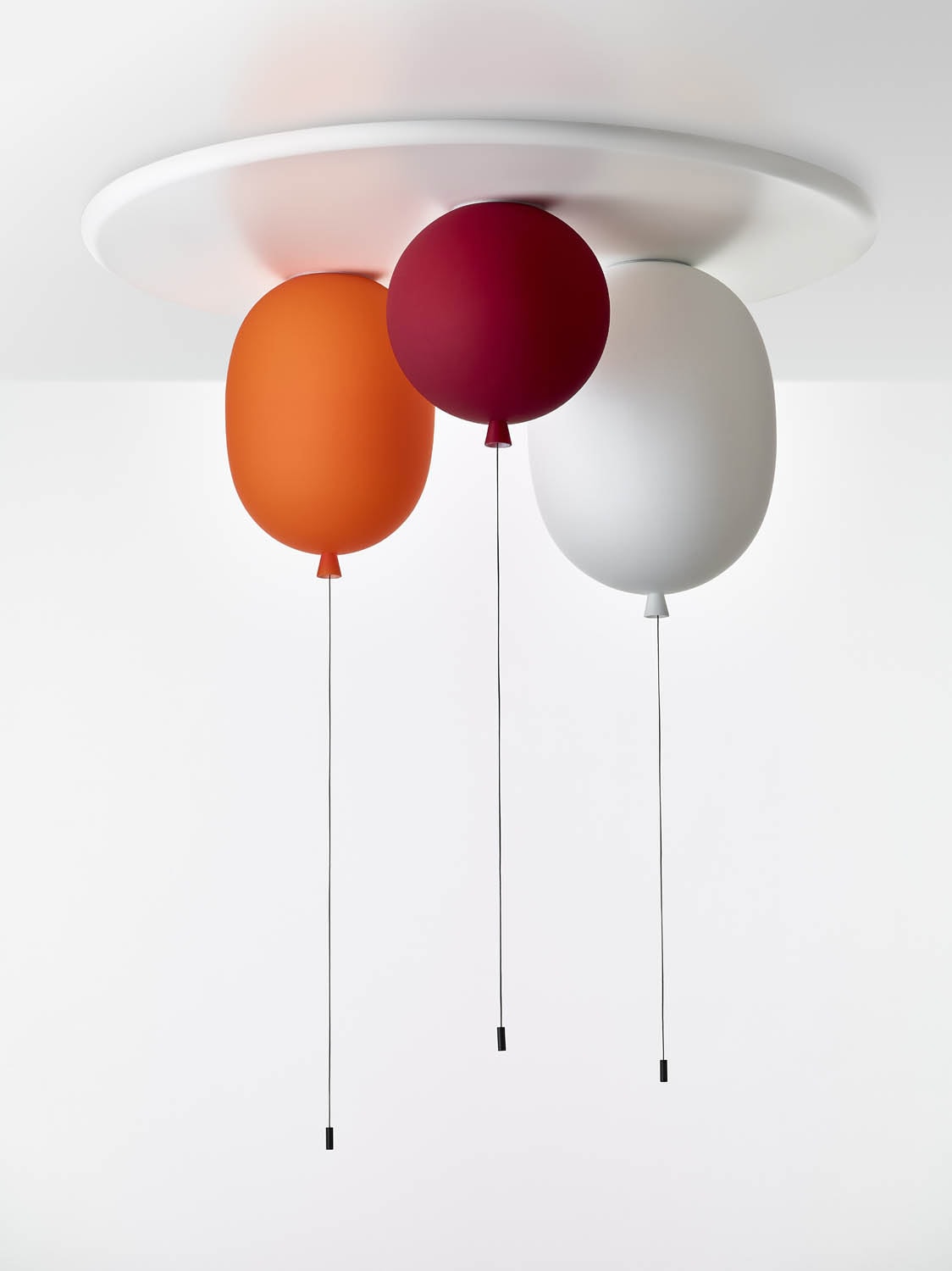 Brokis Memory Set S Oval lights in orange, red, and white float from a ceiling mount, each with elegant cords.
