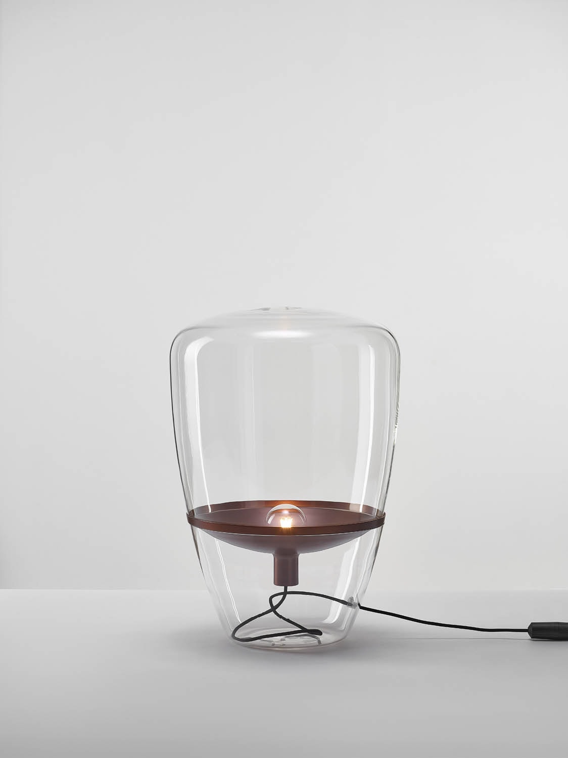 Brokis Balloons Mediam lamp showcases a handblown glass dome atop a copper base, glowing elegantly.