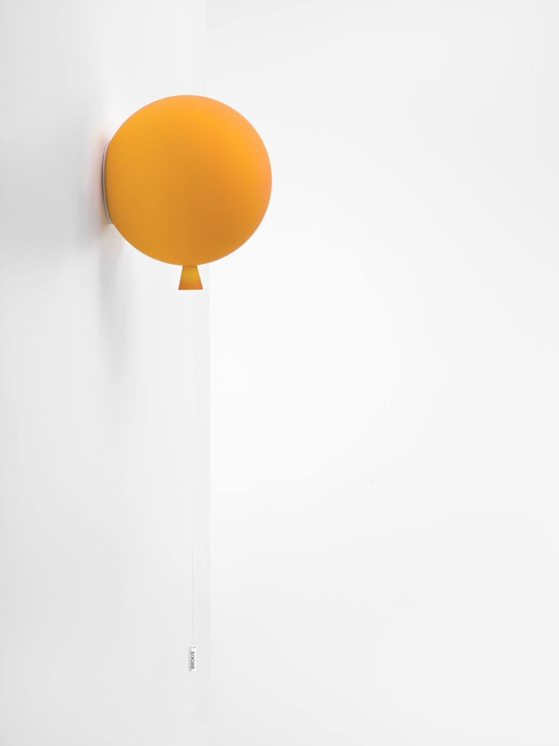 Brokis Memory Wall 250: sculptural, hand-blown orange glass balloon with white string, knot down, on pristine white wall.