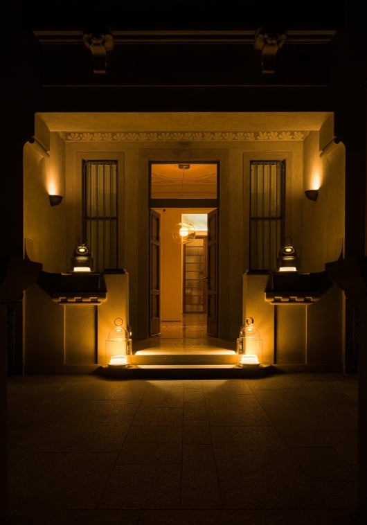 A warmly lit entrance showcases Brokis Dome Nomads and wall sconces, casting a golden glow on refined architectural details.