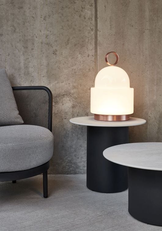 Brokis Dome Nomad Small, handblown with a glowing white dome and copper trim, illuminates an outdoor lounge setting.
