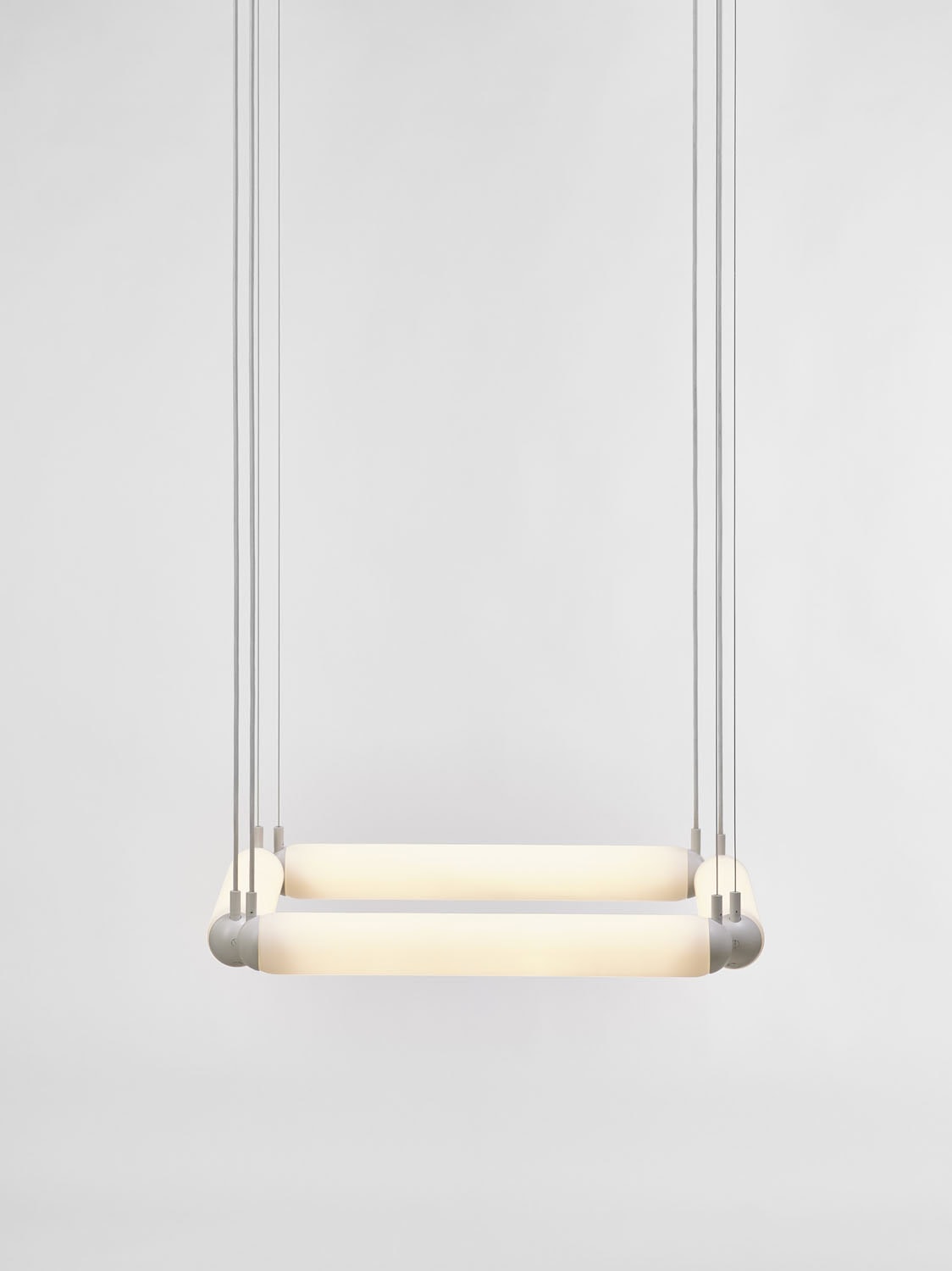 Brokis Puro Contour Square 600 Chandelier showcases sculptural glowing tubes, suspended by cables with a soft white radiance.
