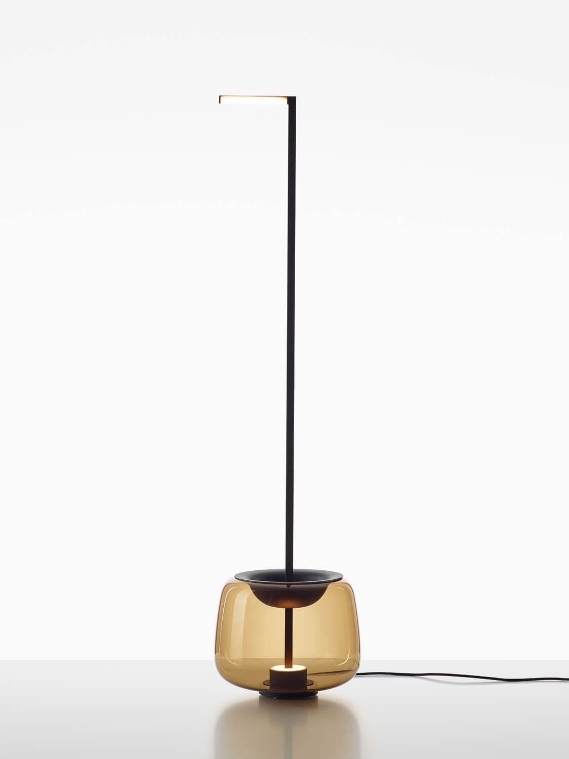 Brokis Double Floor is a sculptural floor lamp with a slim black stem, black horizontal bar, and brown handblown glass base.
