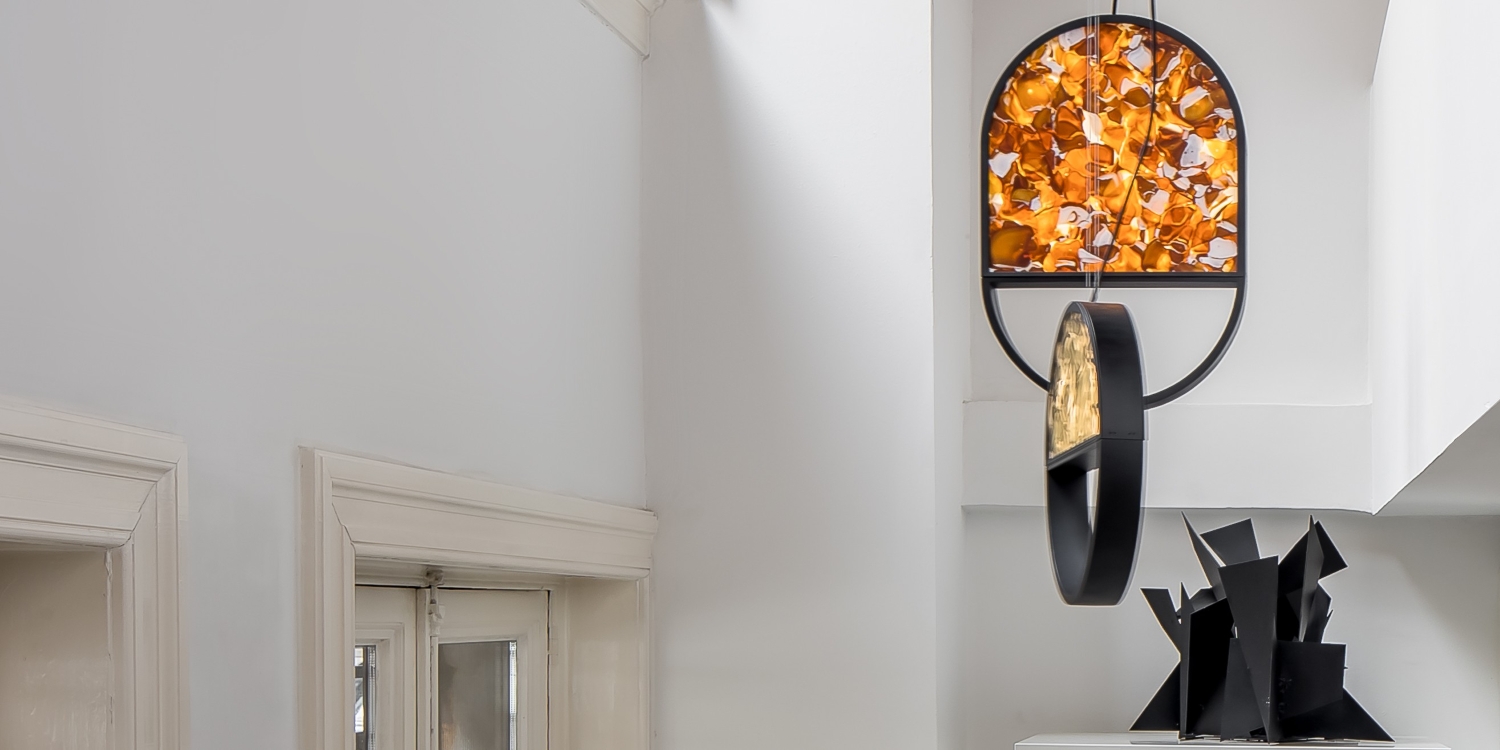 Brokis Geometric pendants in a luminous white interior showcases sculptural black and vibrant abstract art above a door.