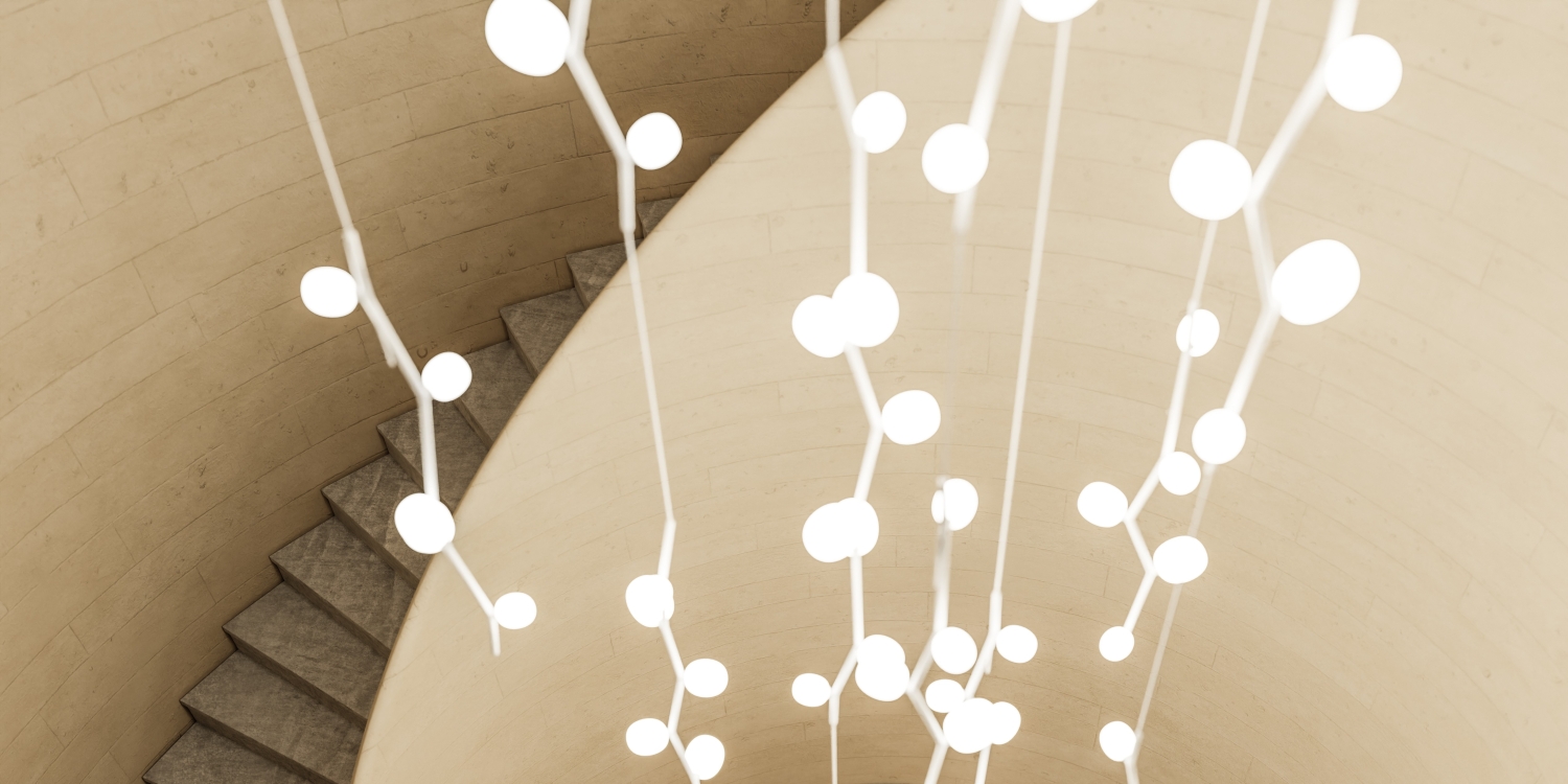 Brokis Ivy Vertical pendants illuminate a curved stone staircase borders a beige wall.
