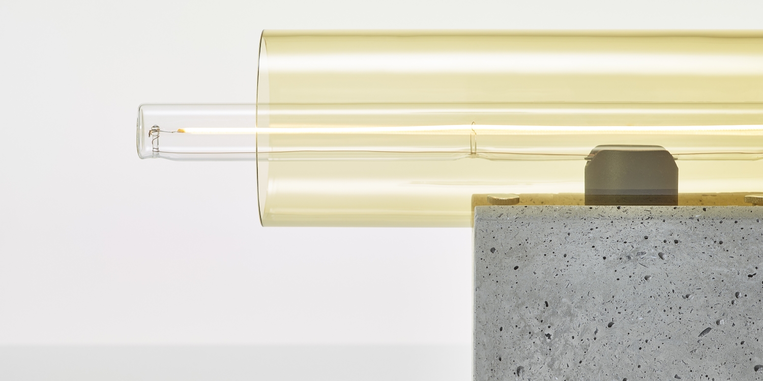 Brokis Overlay Table M lamp with a sculptural amber glass bulb on a sleek concrete base, exuding luxury.