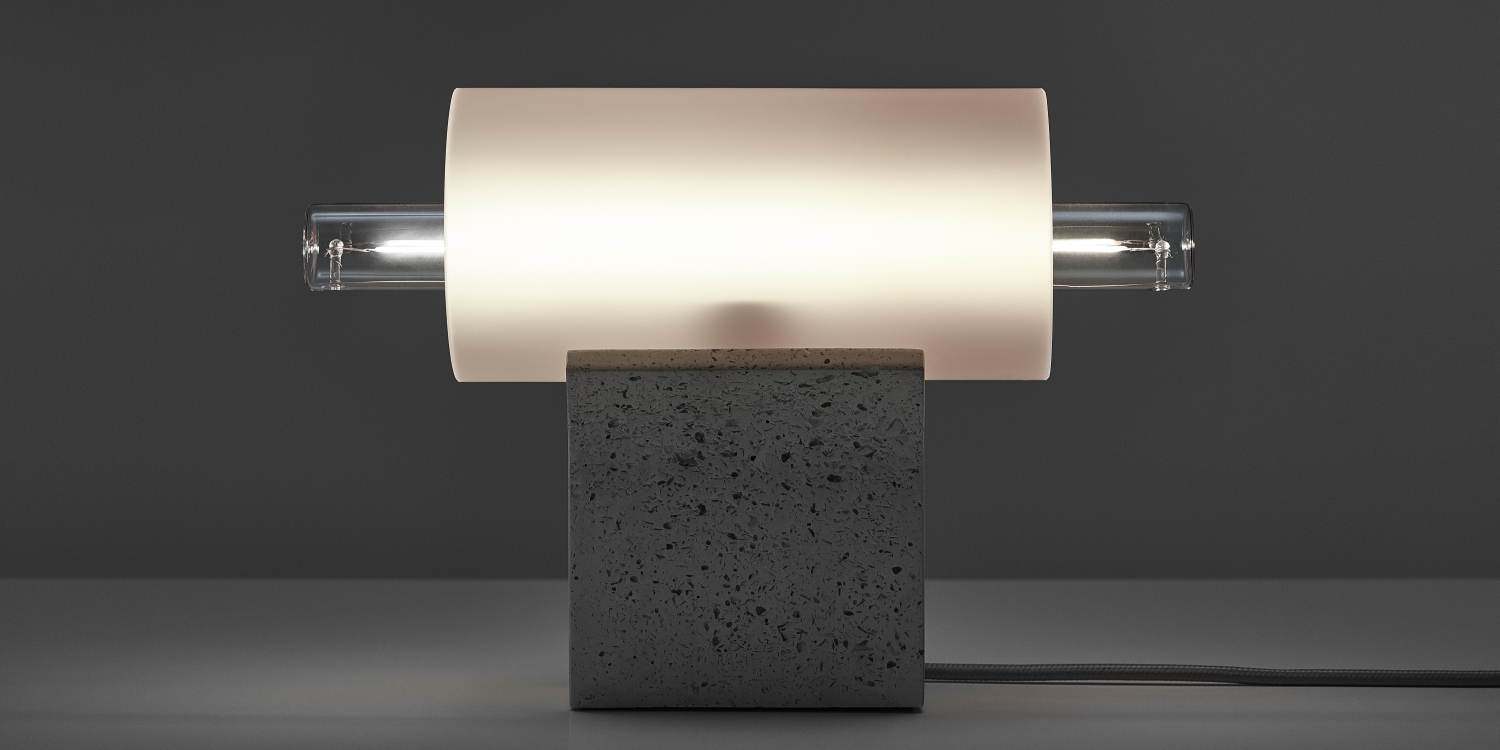 Brokis Overlay Table S is a minimalist lamp with a sculptural concrete base, frosted shade, and handblown glass tube aglow.