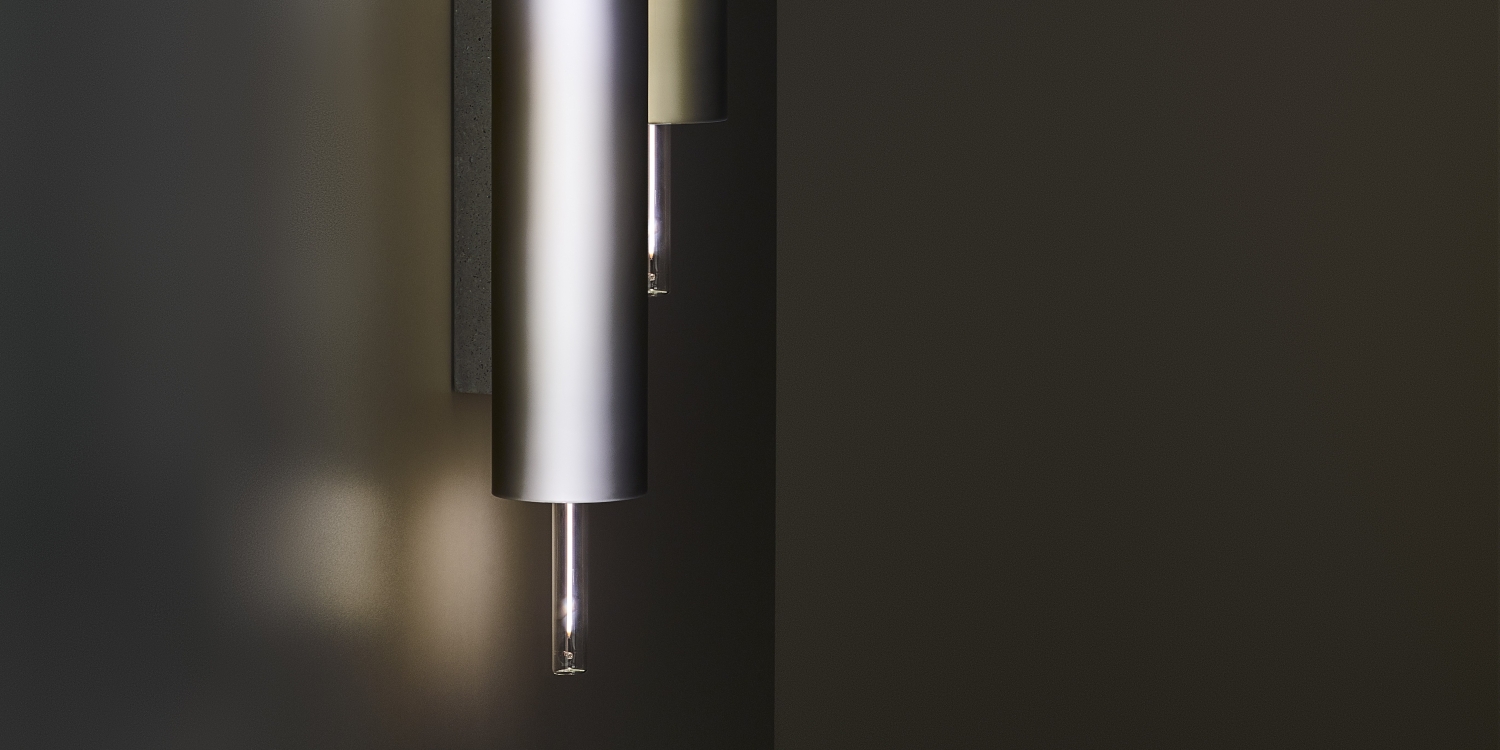 A close-up of two Brokis Overlay Wall L Double sconces, with sculptural glass accents, casting a soft glow on a dark wall.