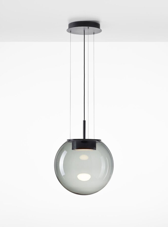 Brokis Orbis 500 Pendant features a smoke grey glass globe, sculptural black core, and glowing bulb on sleek cables.