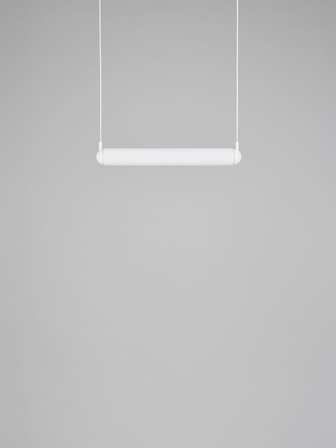 Brokis Puro Solo Horizontal 600, a handblown sculptural pendant, floats on fine cords against a luxe grey backdrop.