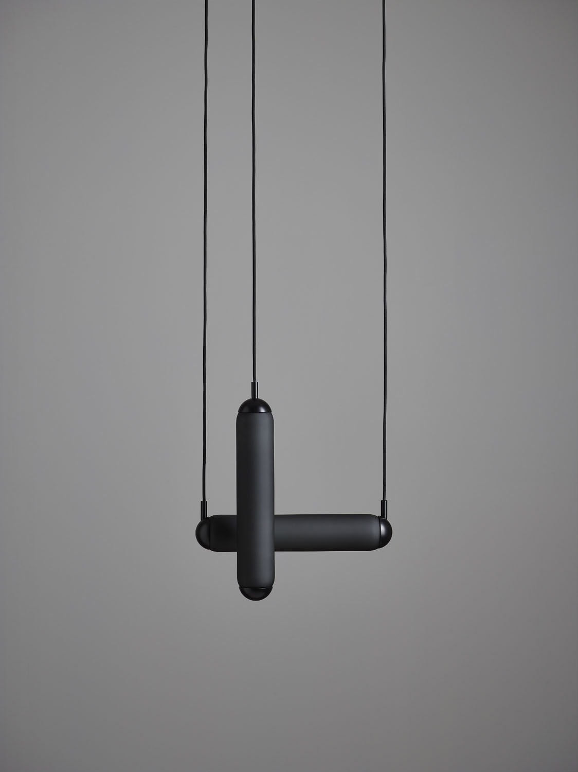 Brokis Puro Solo Vertical 400 Pendant: sculptural matt black cylinders intersect, suspended on sleek cords, exuding luxury.