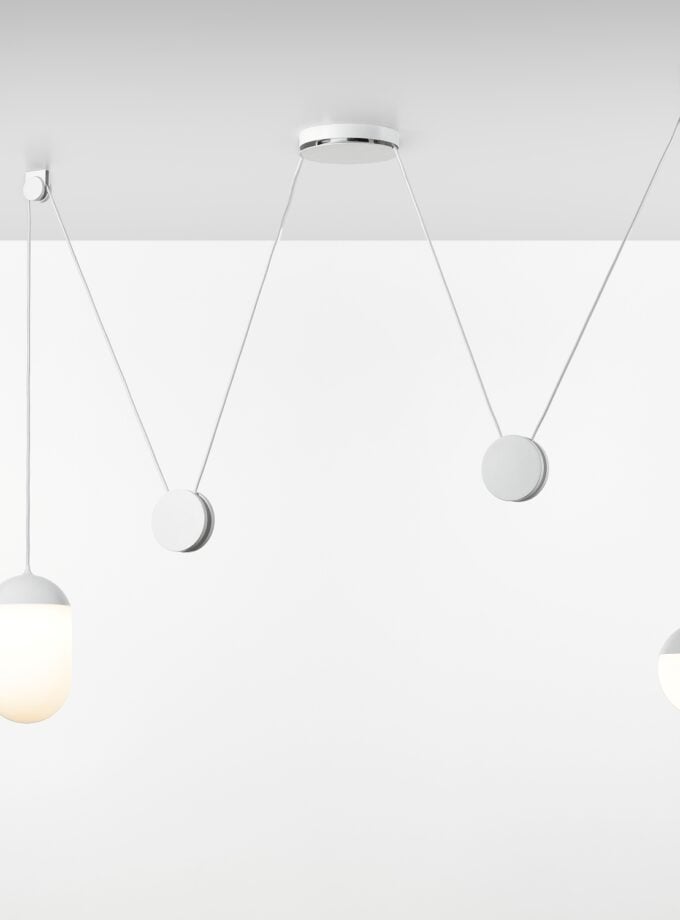 Brokis Planets 2 Set showcases sculptural hand-blown ceiling lights - one elongated aglow, one round unlit - on white cords.