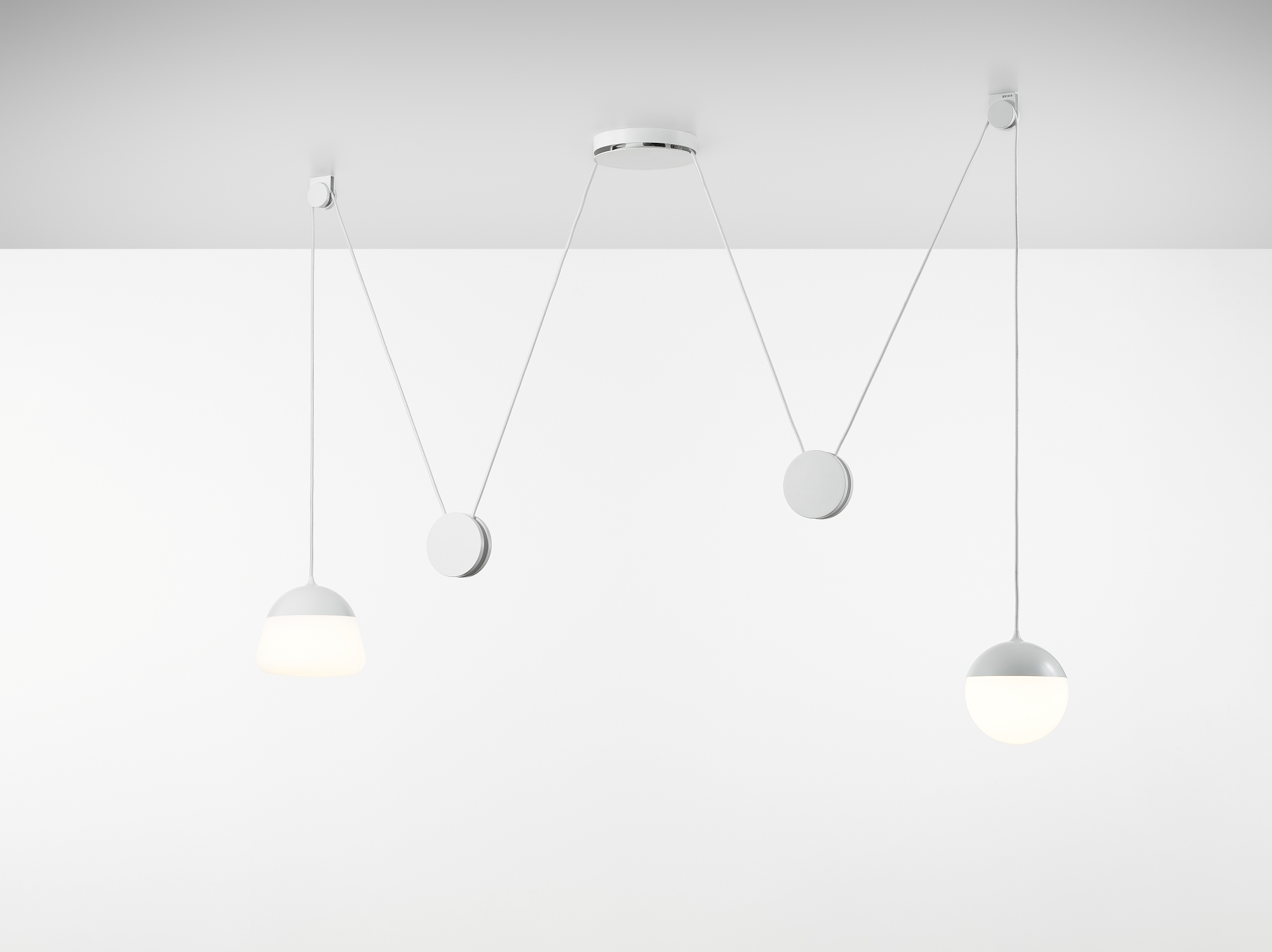 Brokis Planets 2 Set lights in hand-blown glass float at varied heights on a white ceiling, suspended by elegant white cords.