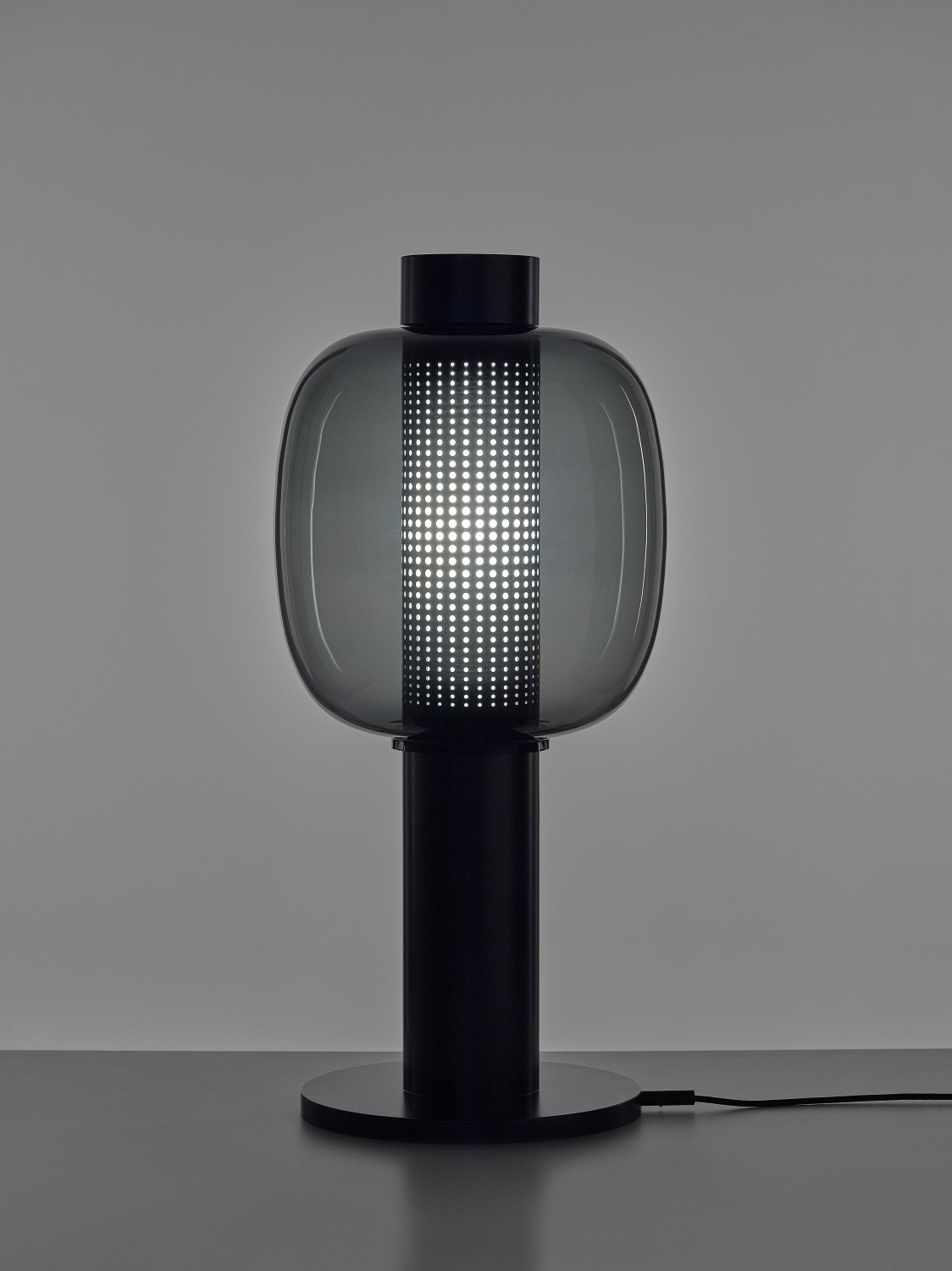 Brokis Bonbori Large lamp pairs a sculptural black base with a grey hand-blown glass shade, casting luminous dotted grids.