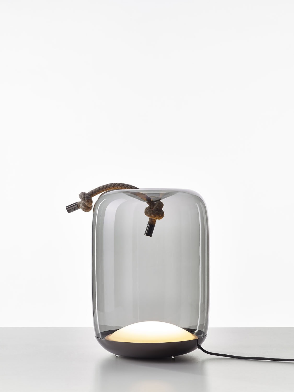 Brokis Knot Cilindro Table: sculptural handblown glass shade, knotted rope handle, glowing base on white background.