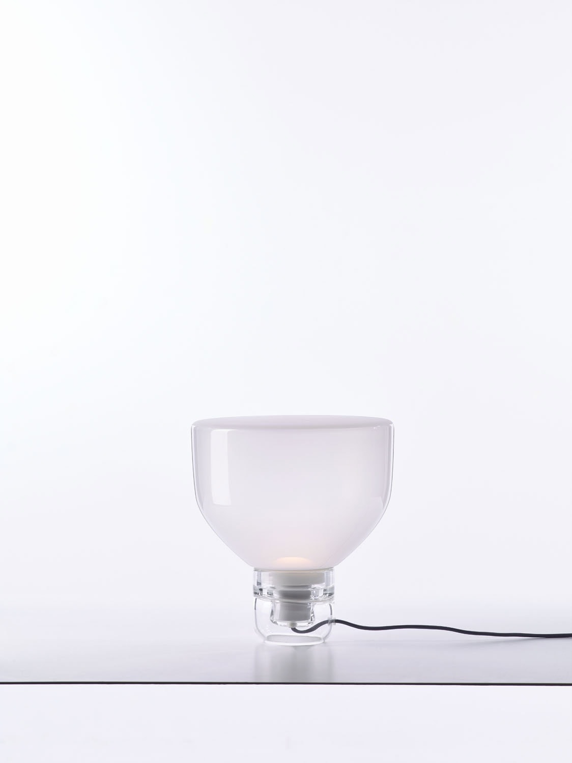 Brokis Lightline S Table lamp features a sculptural, handblown glass shade and clear base on an elegant white surface.