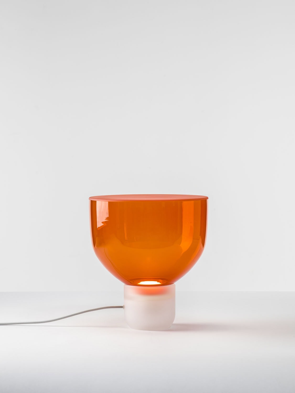 Brokis Lightline S Table lamp stuns with a sculptural white base and glossy, handblown orange glass bowl-shaped shade.
