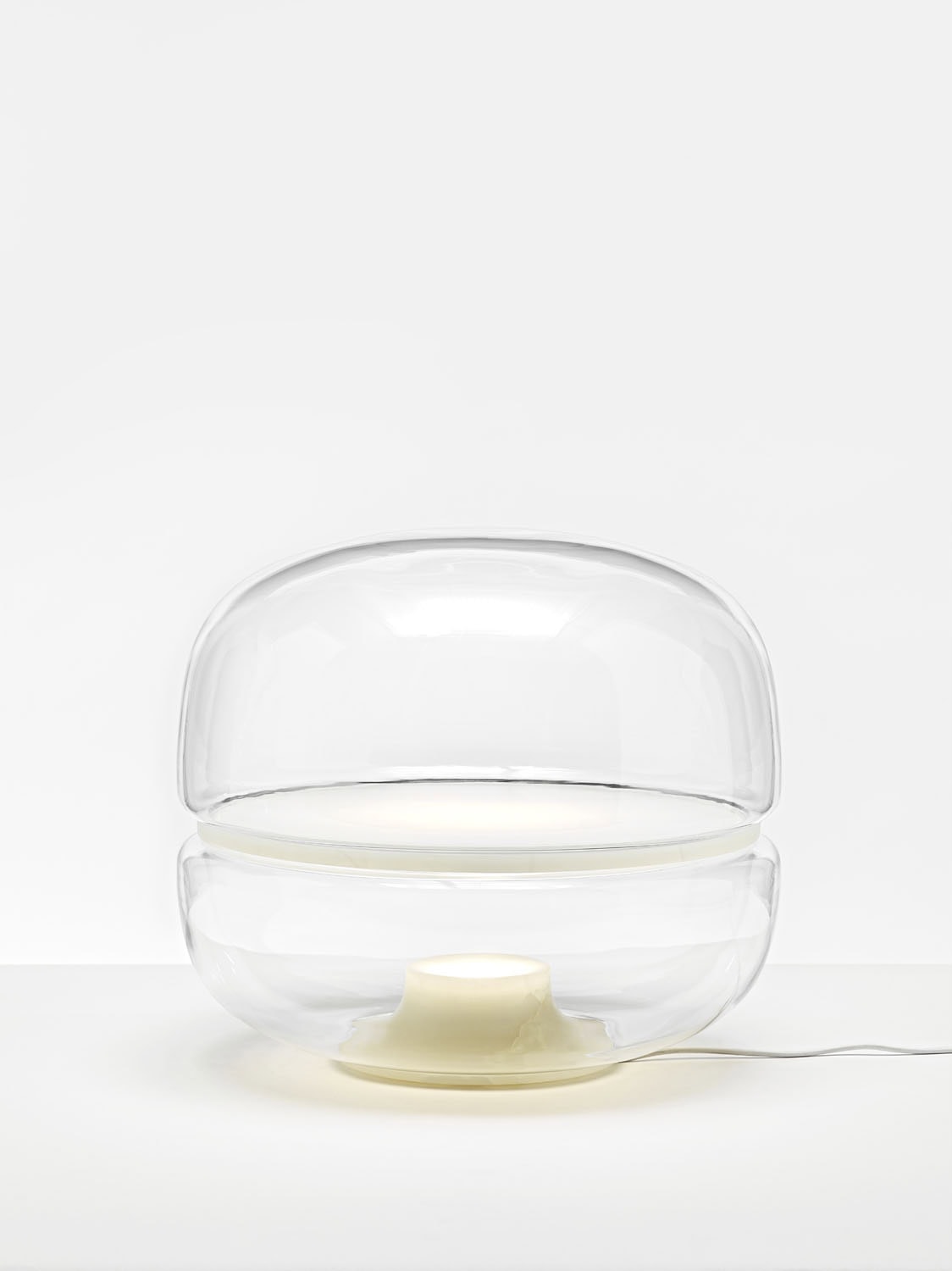 Brokis Macaron L lamp exudes luxury with its handblown glass dome and soft white glow on a pristine surface.