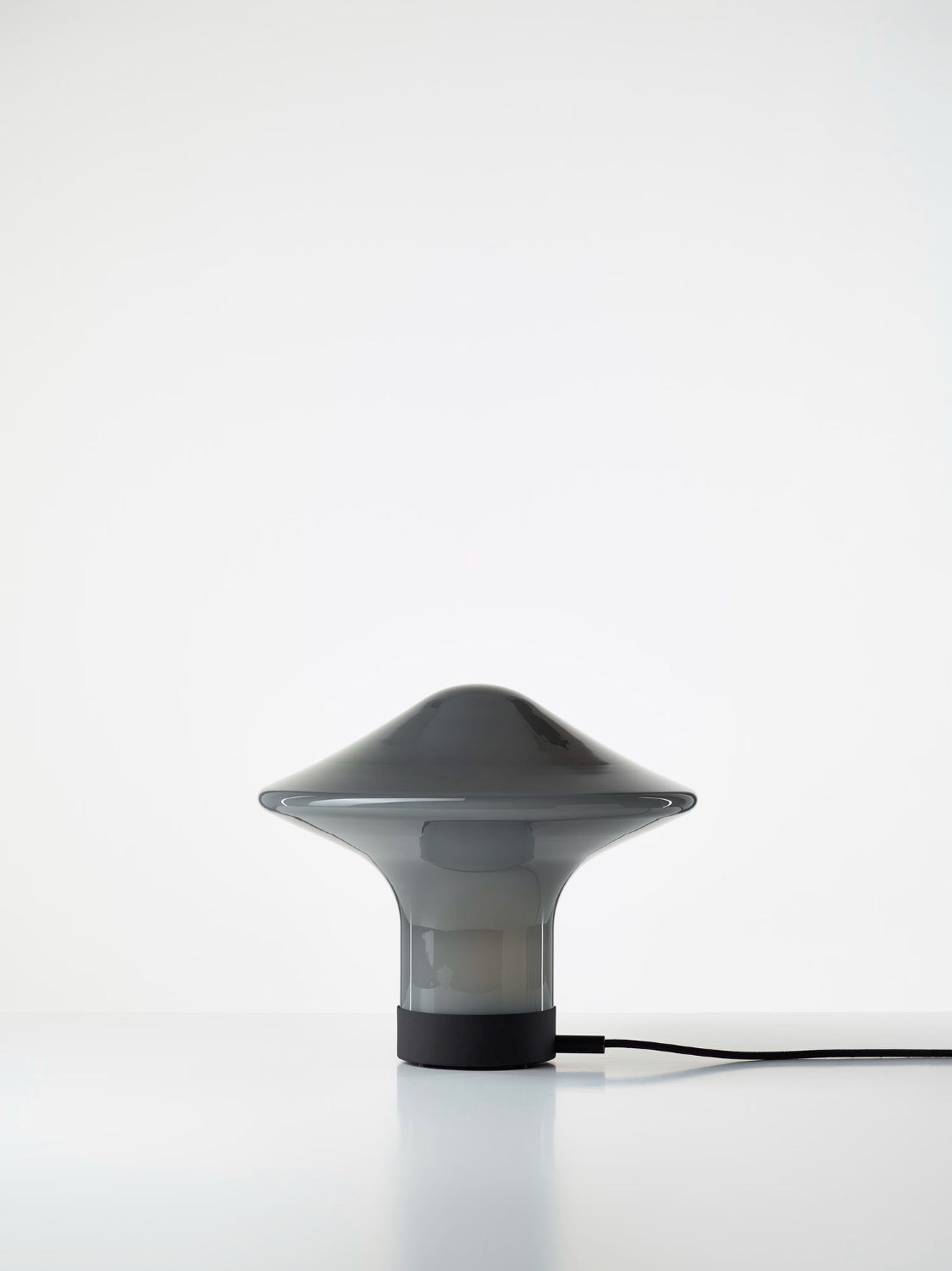 Brokis Trottola Table S features a handblown grey glass dome and sculptural black base, exuding modern luxury.