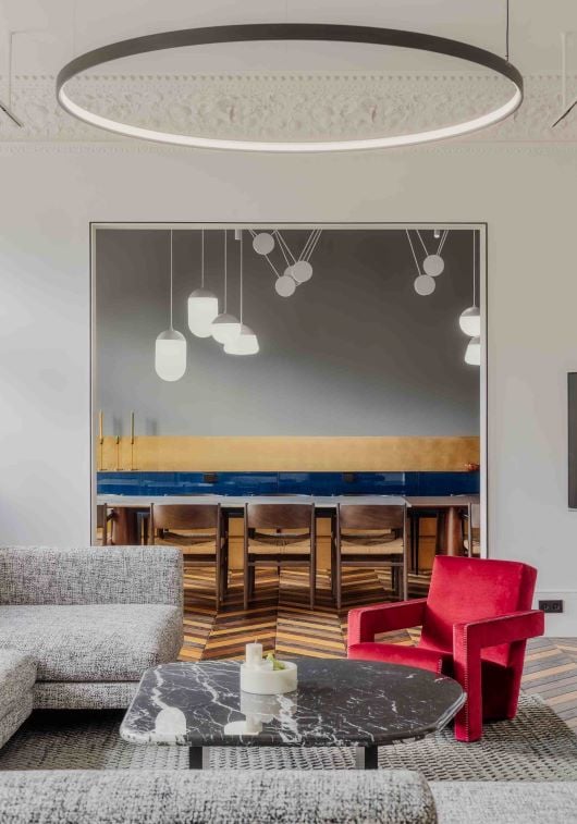 Sophisticated living room with grey sofa, red armchair, black marble table, Brokis Planets 7 Set accenting the dining area.