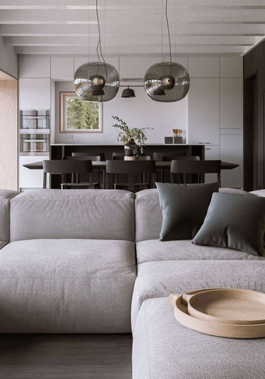 Modern living-dining space with a light grey sectional, dark accents, Brokis Big One Large pendants, and wooded views.