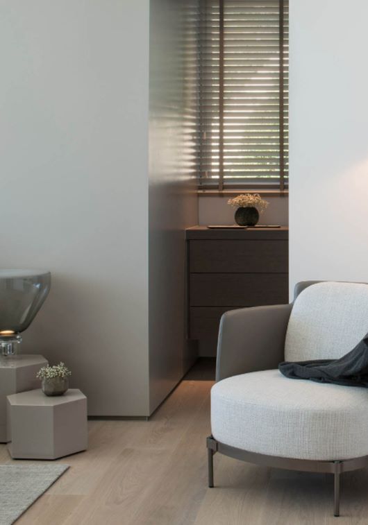 A minimalist living room with light wood floors, a sculptural Brokis Lightline M lamp, and refined modern furnishings.