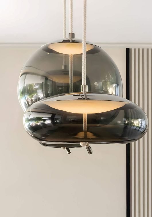 Brokis Knot pendants in glossy, dark crystal glass cast a warm glow, elevating a luxe setting with sculptural elegance.
