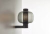 Brokis Bonbori Wall Up sconce with a handblown smoky glass globe and perforated black metal glows luxuriously on the wall.