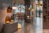 A showroom showcases sculptural Brokis handblown glass and metal lamps, luxe seating, and sunlit polished concrete floors.