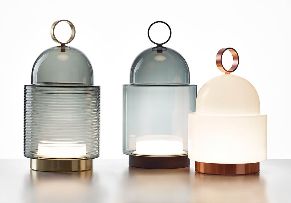 Three Brokis Dome Nomad floor lamps with domed crystal shades and luxe metallic bases in brass, bronze, and copper.