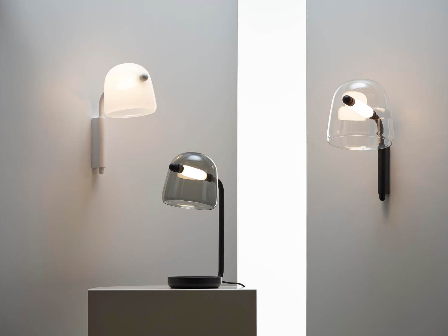 Brokis Mona Small Wall lamps, in black and white, sit elegantly on wall mounts and a central plinth.