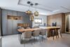 A sleek kitchen with grey and wood cabinetry, white island, taupe chairs, and Brokis Double pendant lights.