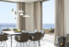 Elegant dining room with dark table, eight grey chairs, Brokis Shadows pendants, ocean-view balcony, and minimalist décor.