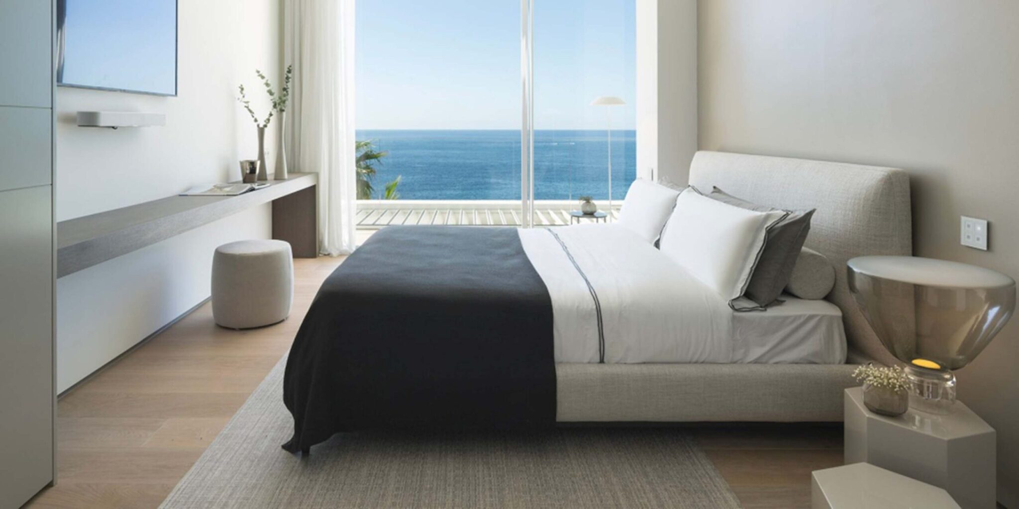 Luxurious modern bedroom with a  Brokis Lightline M, plush bed, minimalist accents, and sunlit wooden floors.