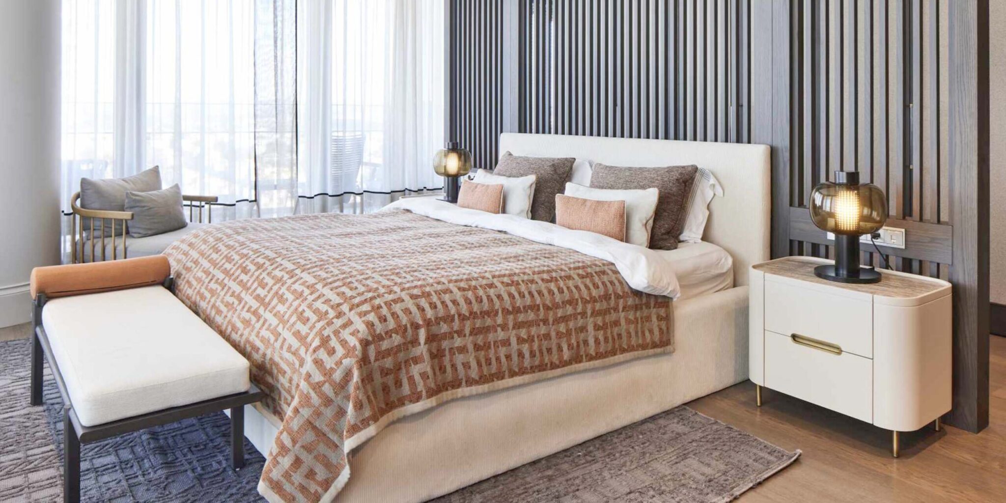 Luxurious bedroom with an upholstered bed, geometric bedlinen, Brokis Bonbori Table lamps, and floor-to-ceiling windows.