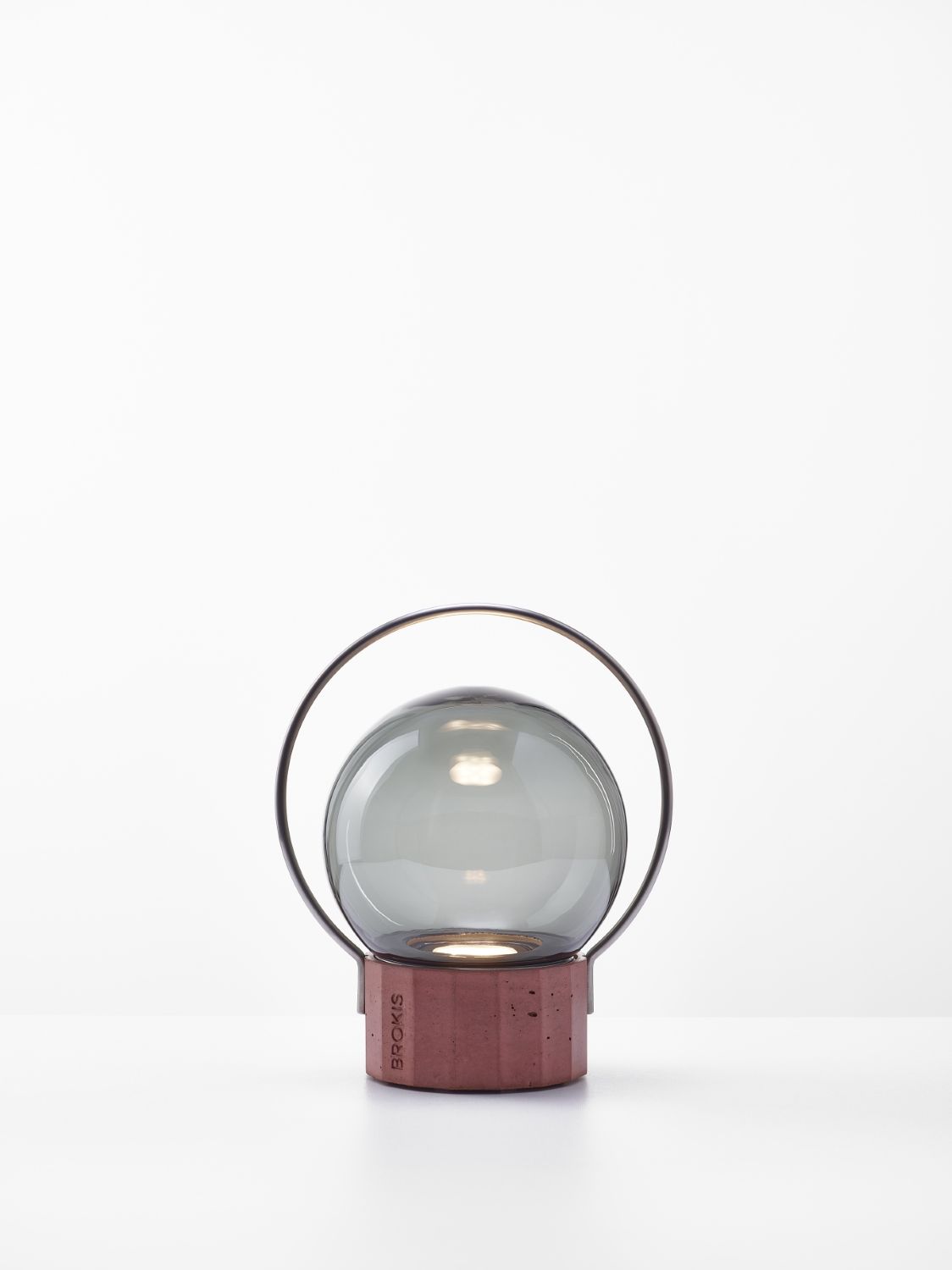 Brokis Sfera Portable Small lamp with a grey handblown glass globe and terracotta base, accented by an arched metal handle.