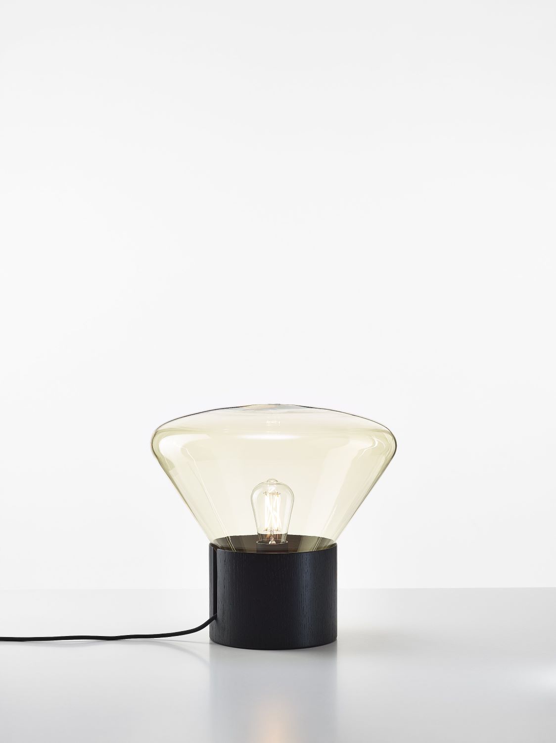 Brokis Muffins 01 Table lamp with transparent glass shade and visible bulb, exuding elegance on a minimal surface.