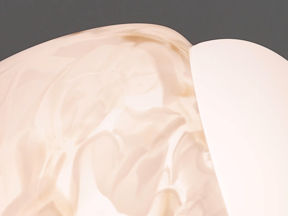 A close-up of a Brokis Capsula surface with glossy triplex opal marbling, against a soft grey backdrop - abstract luxury.