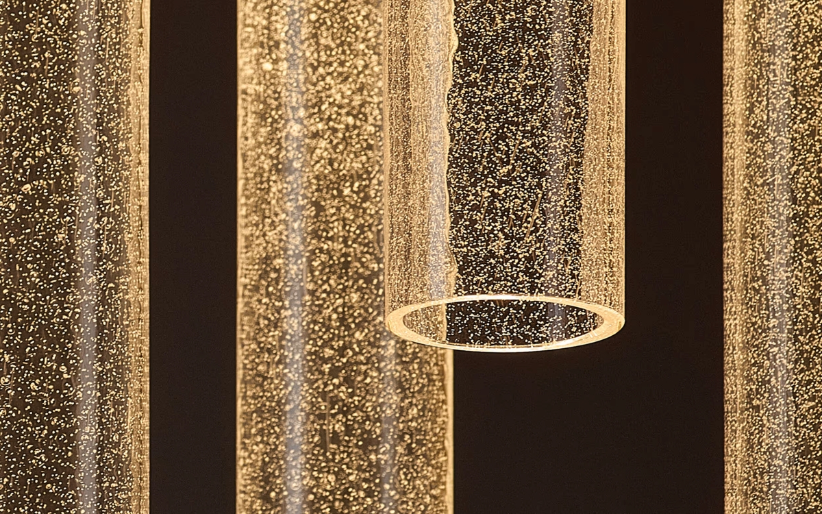 Brokis Comet Round pendants, suspended, glow with warm light and silica against a dark, luxurious backdrop.