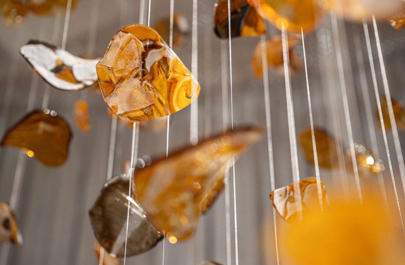 Close-up of BROKISGLASS Bloom petals on fine wires; luminous, glossy forms reflect warm light.