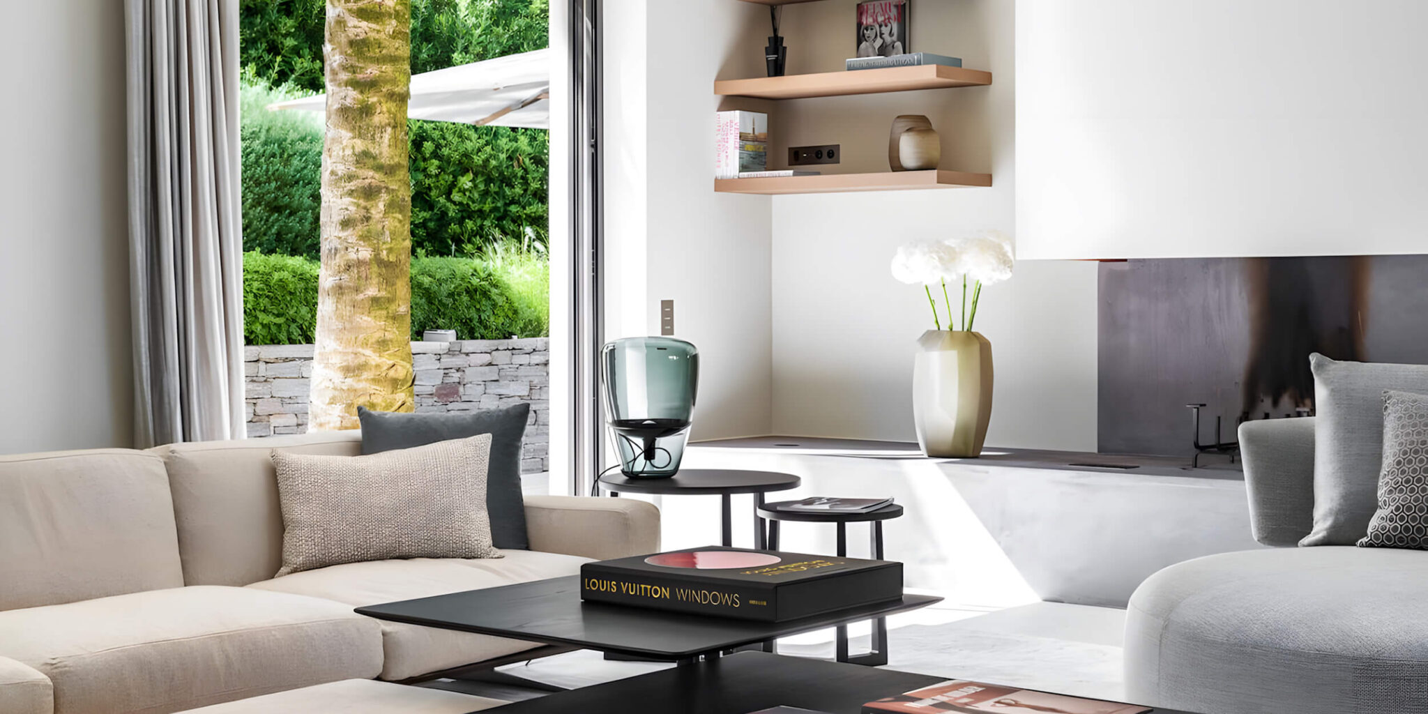 Luxurious living room with beige sofa, Brokis Balloons Large, white blooms, and garden views through wide windows.