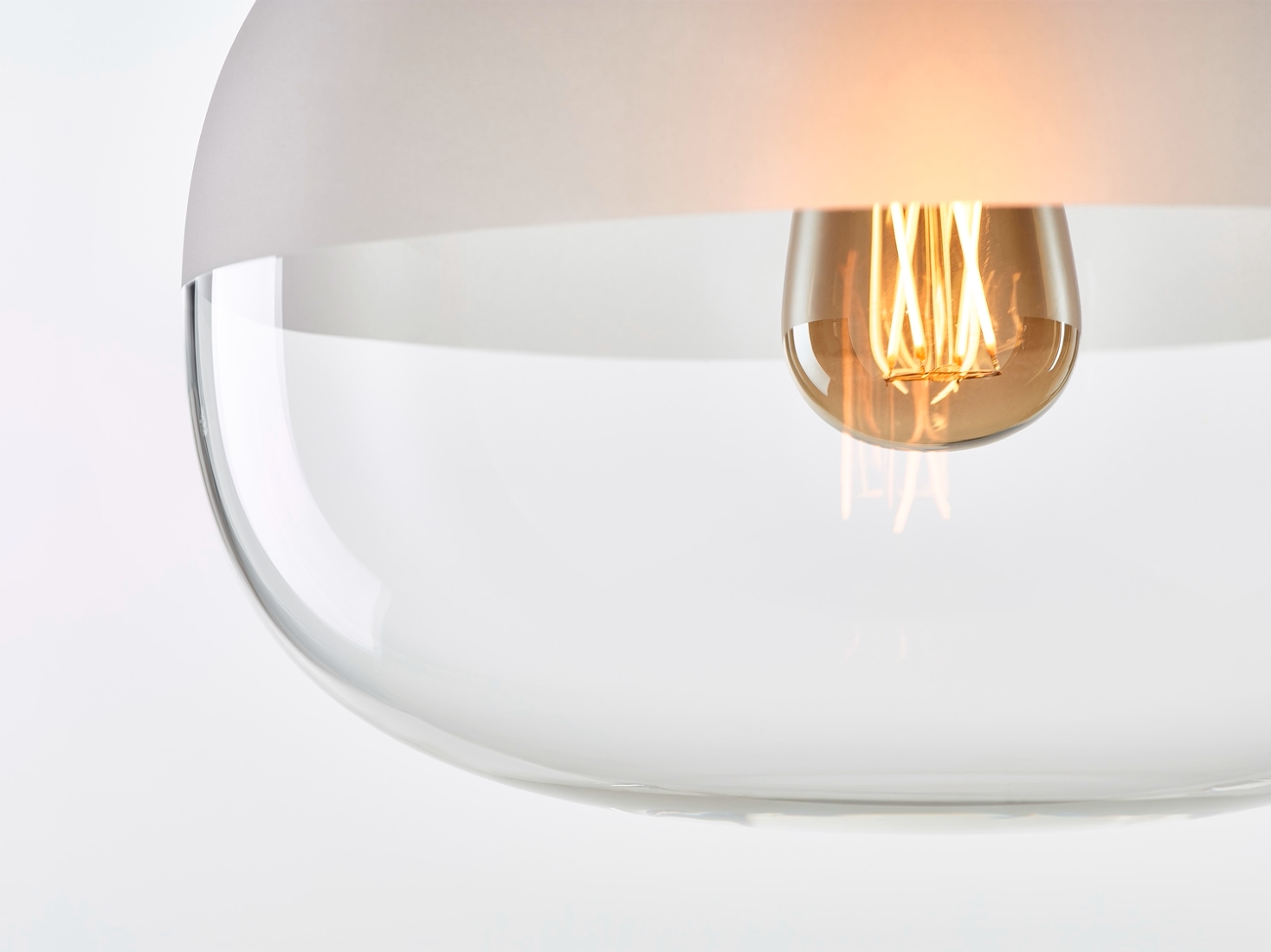 Brokis Awa Medium Pendant in handblown clear glass, matt white accent, and warm filament glow exude modern luxury.