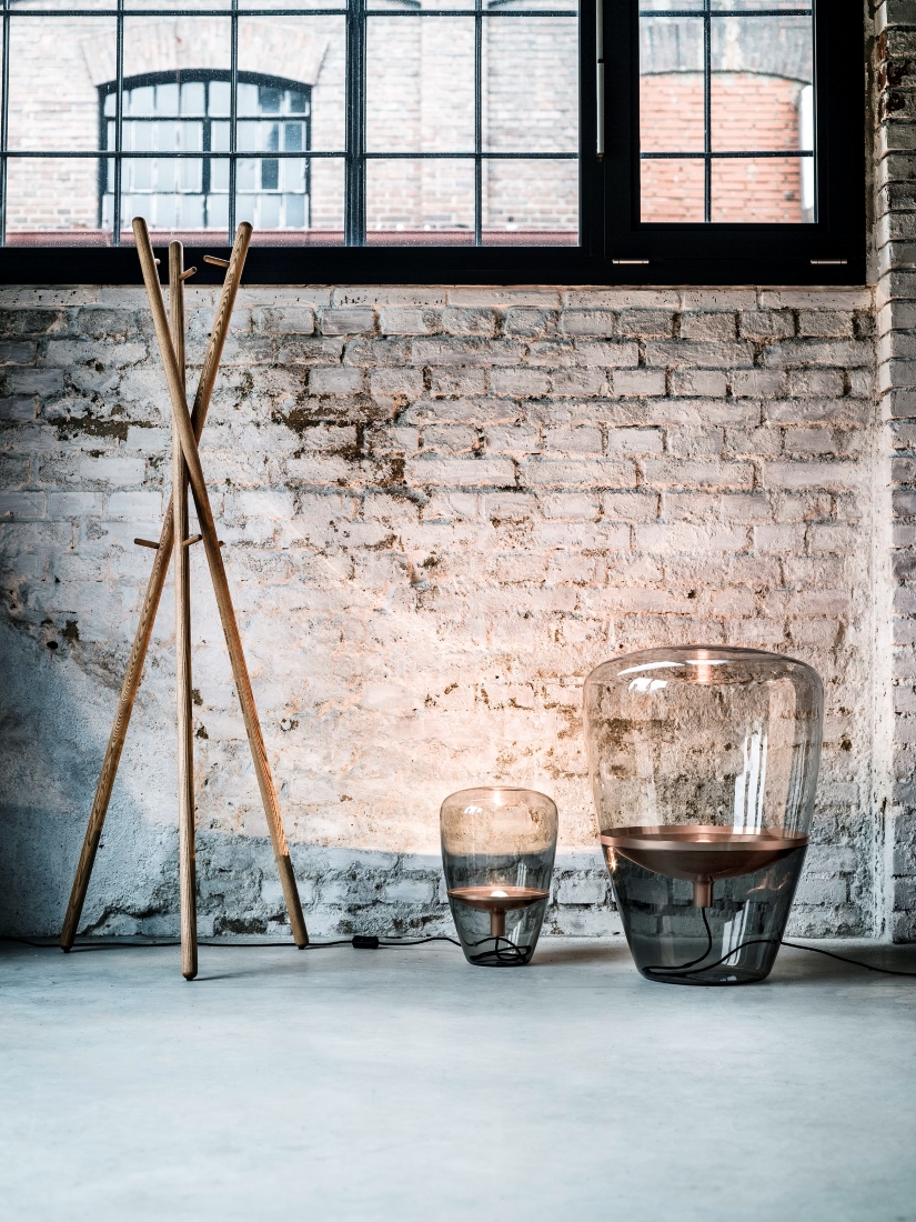 A sunlit, loft-style interior with exposed white brick, Brokis Balloons glass floor lamps, and sleek wood accents.