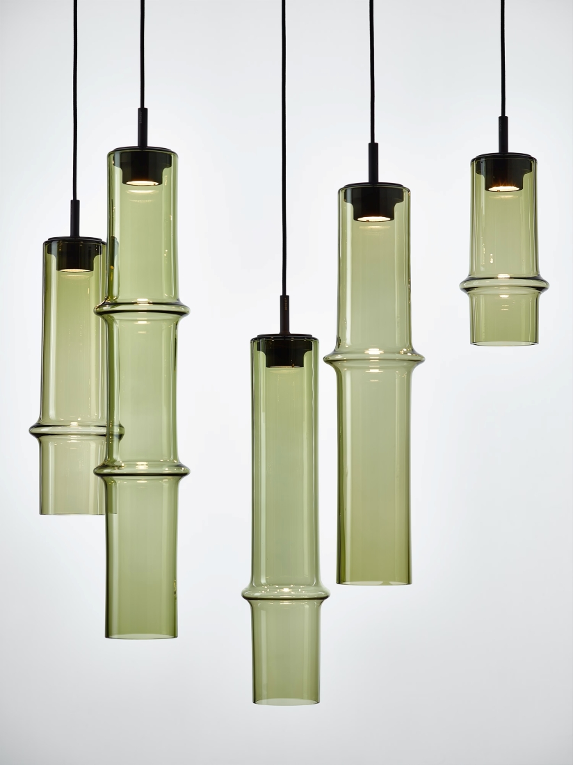 Five Brokis Bamboo Forest pendants with sculptural, green-tinted glass shades hang in a luxe, staggered display.