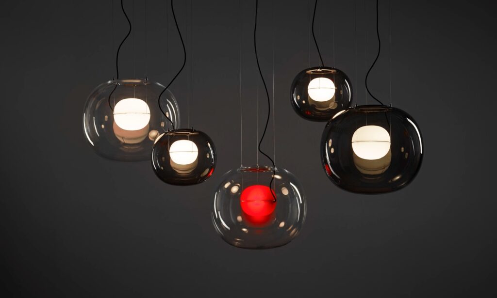 Six Brokis Big One pendants in glass float at varied heights; one glows red, five emit a soft white shimmer.